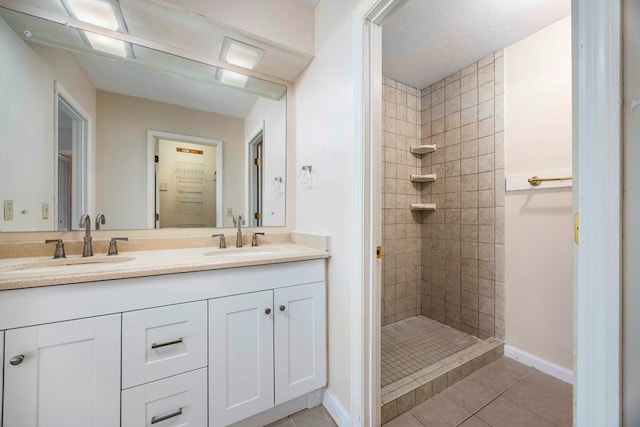 bathroom with tile patterned floors, a textured ceiling, vanity, and a tile shower