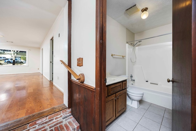 full bathroom with tile patterned floors, shower / bath combination, a textured ceiling, toilet, and vanity