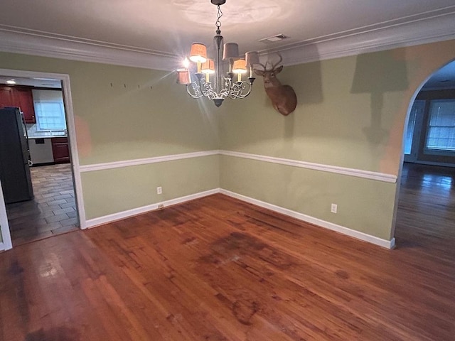 unfurnished dining area featuring dark hardwood / wood-style flooring, ornamental molding, and a chandelier