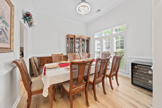 dining space with crown molding, wainscoting, light wood-type flooring, and visible vents