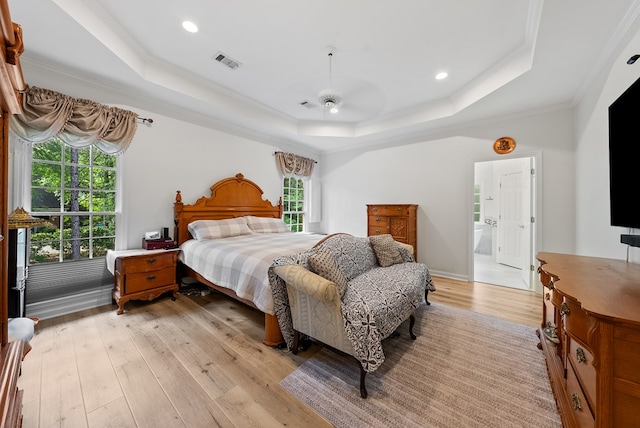 bedroom with crown molding, visible vents, a raised ceiling, and light wood-type flooring