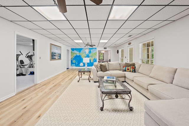 living room featuring a paneled ceiling, baseboards, a wealth of natural light, and wood finished floors