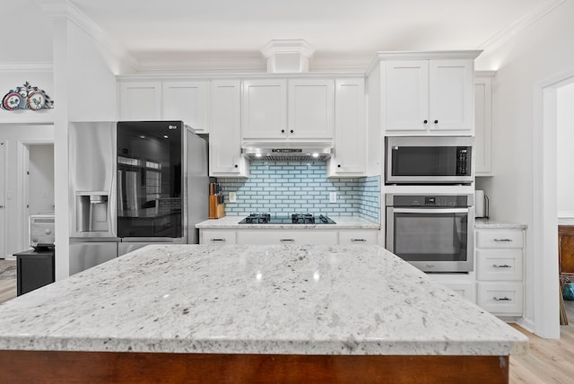 kitchen with under cabinet range hood, white cabinets, appliances with stainless steel finishes, and a center island