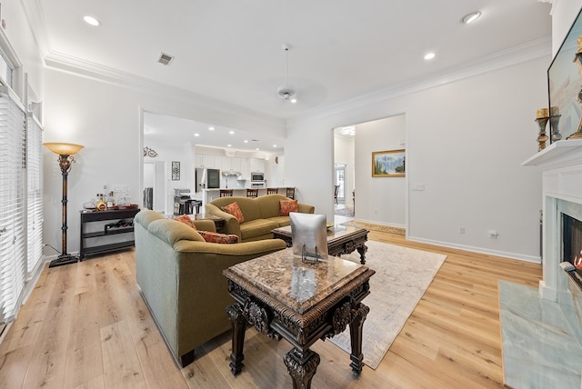 living area featuring visible vents, a high end fireplace, crown molding, light wood finished floors, and recessed lighting