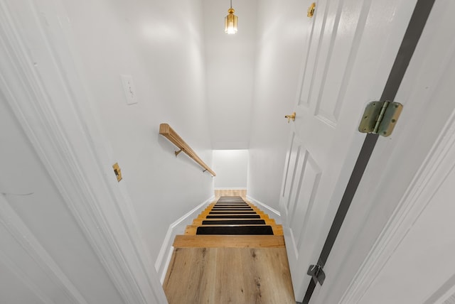 staircase featuring baseboards and wood finished floors