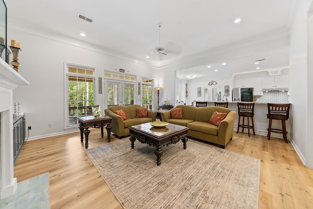 living room with a premium fireplace, ceiling fan, visible vents, and ornamental molding