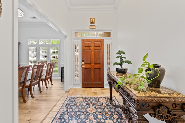 foyer featuring crown molding, baseboards, a high ceiling, and visible vents