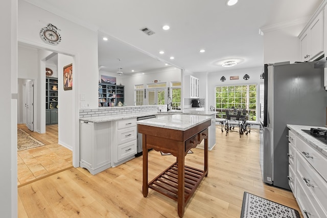 kitchen featuring visible vents, tasteful backsplash, a sink, a peninsula, and stainless steel appliances
