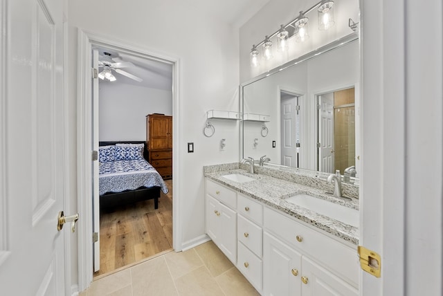 ensuite bathroom with a sink, tile patterned flooring, a shower stall, and double vanity
