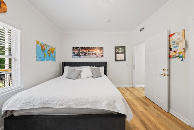 bedroom featuring crown molding, visible vents, multiple windows, and light wood-style floors