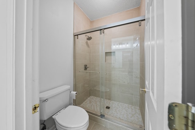 full bath with tile patterned flooring, a textured ceiling, a stall shower, and toilet