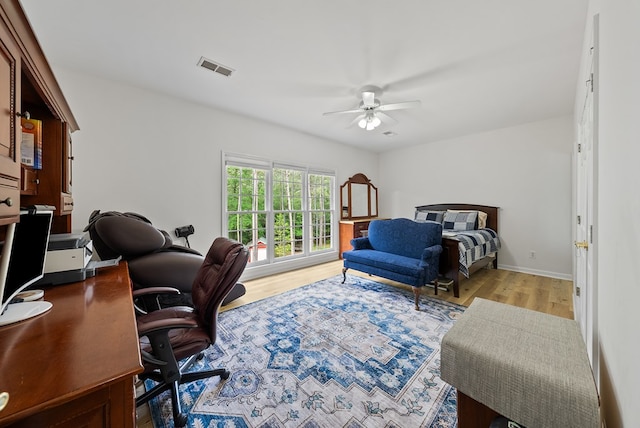 bedroom with baseboards, ceiling fan, visible vents, and wood finished floors