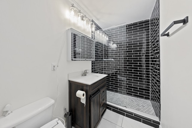 bathroom with vanity, tile patterned flooring, a tile shower, and toilet
