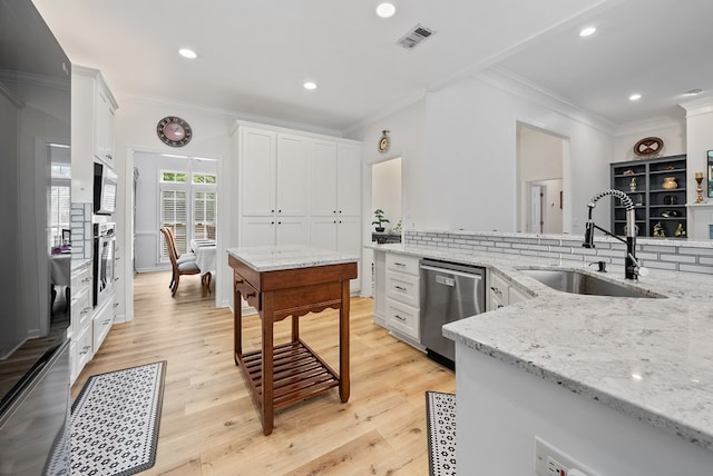 kitchen featuring a sink, appliances with stainless steel finishes, crown molding, and white cabinets