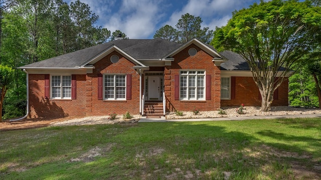 ranch-style house featuring brick siding, a front yard, and roof with shingles