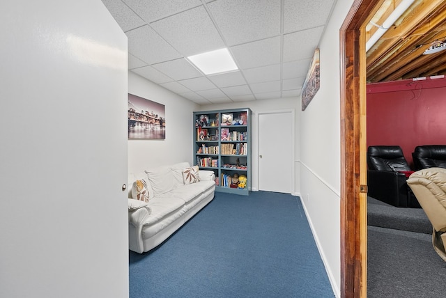 living area featuring carpet flooring and a paneled ceiling