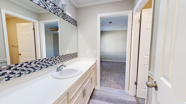 bathroom featuring vanity, hardwood / wood-style flooring, crown molding, and ceiling fan