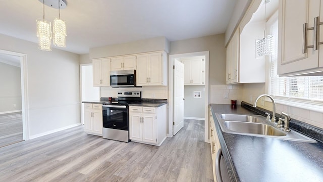 kitchen with sink, appliances with stainless steel finishes, white cabinetry, backsplash, and decorative light fixtures