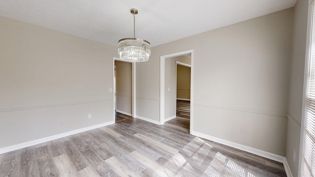 unfurnished room featuring hardwood / wood-style floors and a notable chandelier