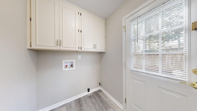 clothes washing area featuring electric dryer hookup, hookup for a washing machine, cabinets, a textured ceiling, and light wood-type flooring