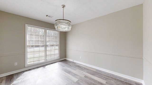 unfurnished room featuring wood-type flooring, a chandelier, and a textured ceiling