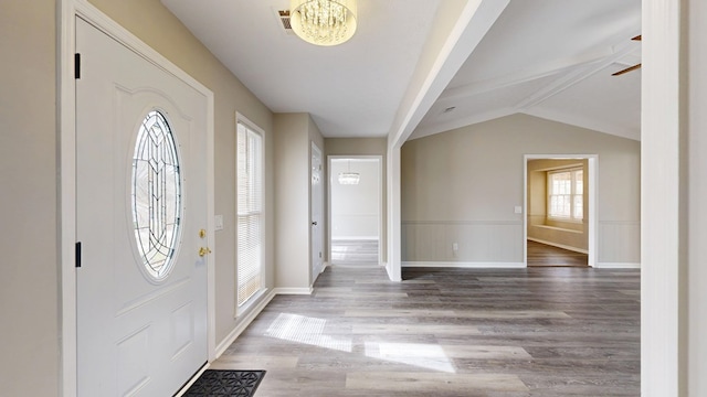 foyer with hardwood / wood-style flooring, a chandelier, and vaulted ceiling with beams