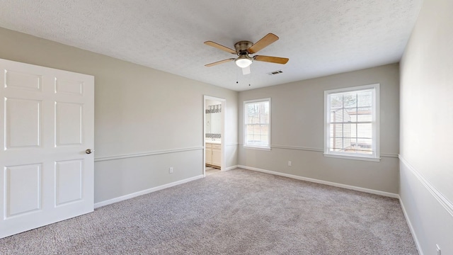 empty room featuring ceiling fan, light colored carpet, and a textured ceiling