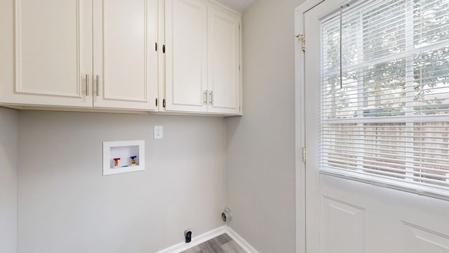 clothes washing area featuring cabinets, hardwood / wood-style flooring, and washer hookup