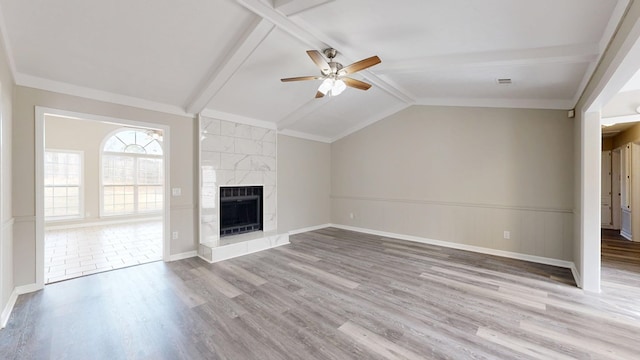 unfurnished living room with ceiling fan, vaulted ceiling with beams, a fireplace, and light hardwood / wood-style floors