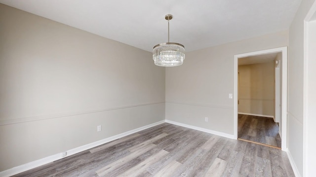 empty room featuring hardwood / wood-style floors and an inviting chandelier