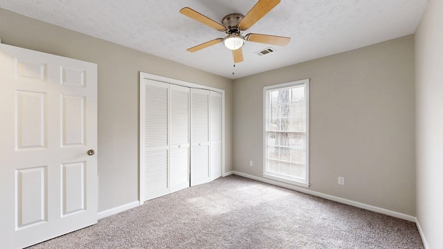 unfurnished bedroom with ceiling fan, light colored carpet, a closet, and a textured ceiling