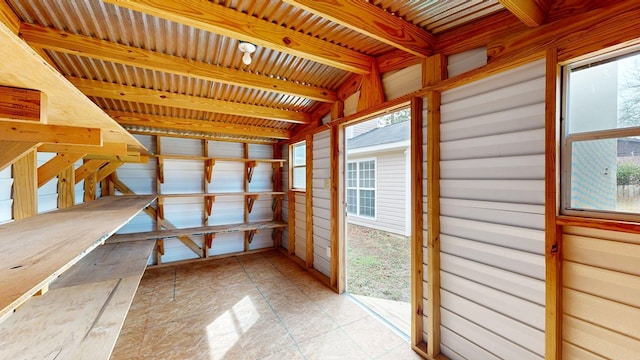 unfurnished sunroom featuring beamed ceiling and a healthy amount of sunlight