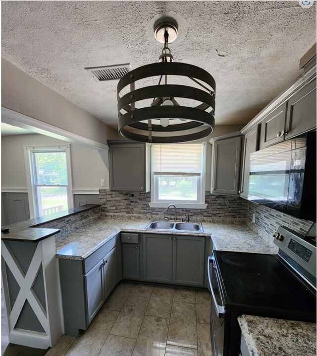 kitchen with electric stove, sink, hanging light fixtures, and gray cabinetry