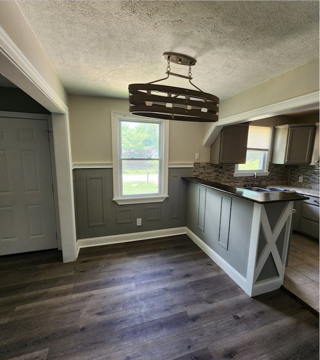 kitchen featuring hanging light fixtures, sink, dark wood-type flooring, and kitchen peninsula