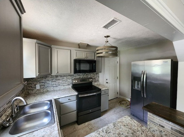 kitchen featuring pendant lighting, sink, gray cabinetry, backsplash, and stainless steel appliances