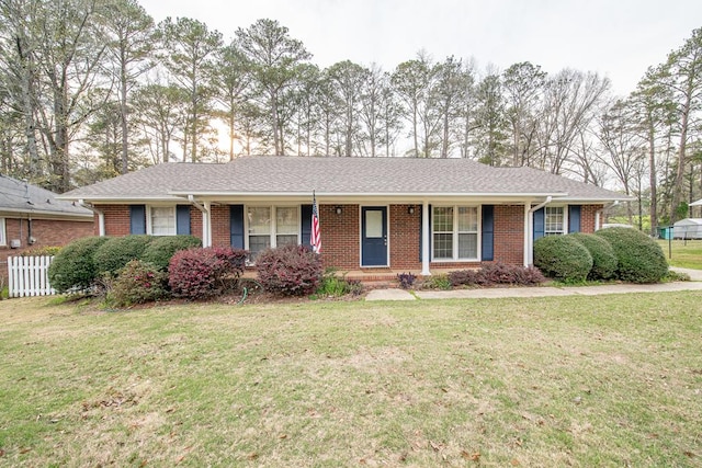single story home featuring brick siding, covered porch, a front yard, and fence