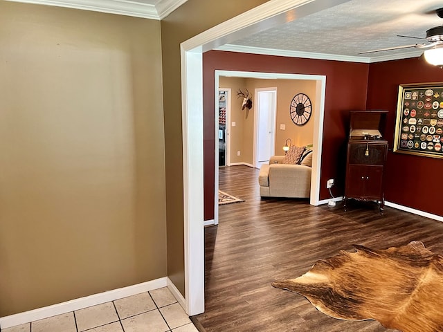 hallway featuring crown molding, wood finished floors, baseboards, and a textured ceiling