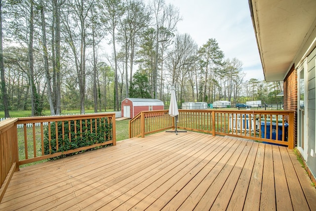 wooden terrace with a storage unit, an outbuilding, a yard, and fence