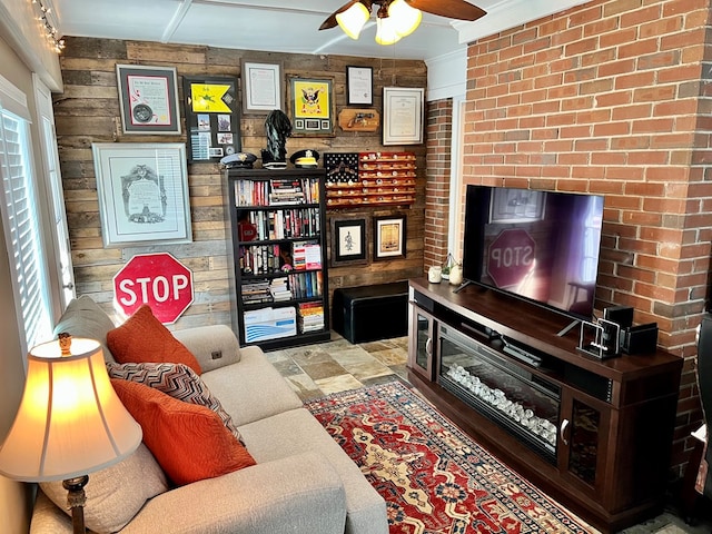 living room with wooden walls, stone finish flooring, brick wall, and ceiling fan