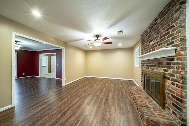 unfurnished living room with visible vents, a brick fireplace, baseboards, dark wood-style floors, and a ceiling fan