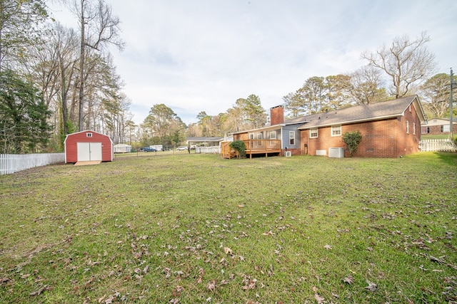 view of yard with fence, a wooden deck, a storage shed, a garage, and an outdoor structure