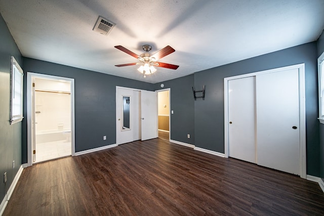 unfurnished bedroom featuring visible vents, connected bathroom, baseboards, wood finished floors, and a textured ceiling