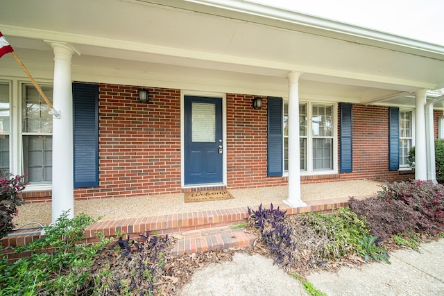 doorway to property with brick siding and a porch