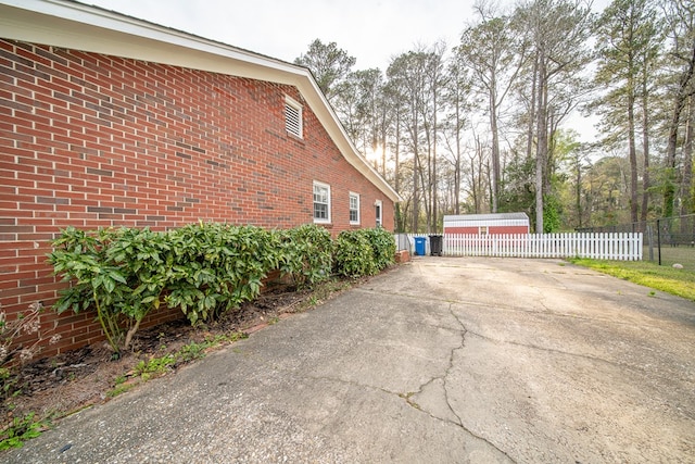 view of side of home featuring fence and brick siding