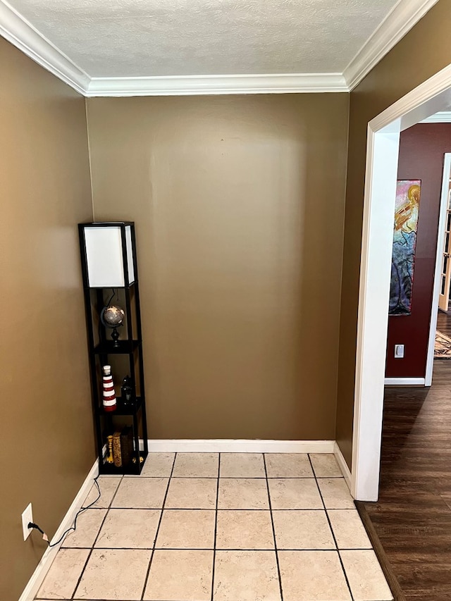 hall featuring crown molding, light tile patterned flooring, baseboards, and a textured ceiling