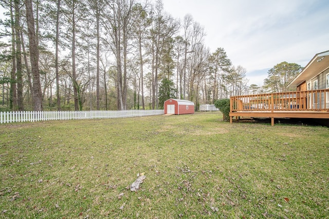 view of yard with a deck, an outbuilding, a fenced backyard, and a shed