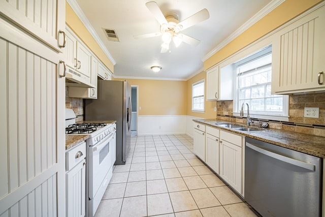 kitchen featuring white gas stove, under cabinet range hood, dishwasher, light tile patterned floors, and a sink