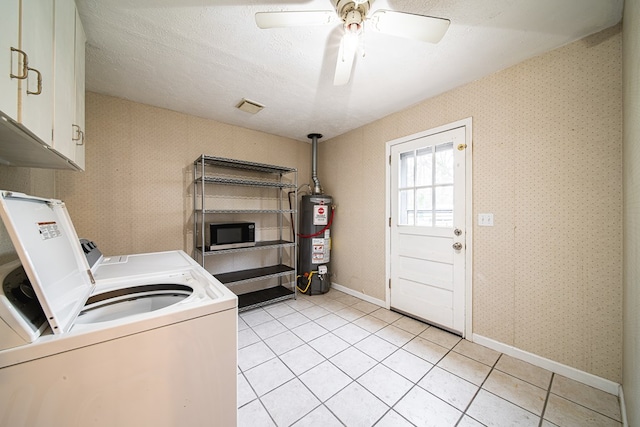washroom with a textured ceiling, water heater, cabinet space, separate washer and dryer, and wallpapered walls