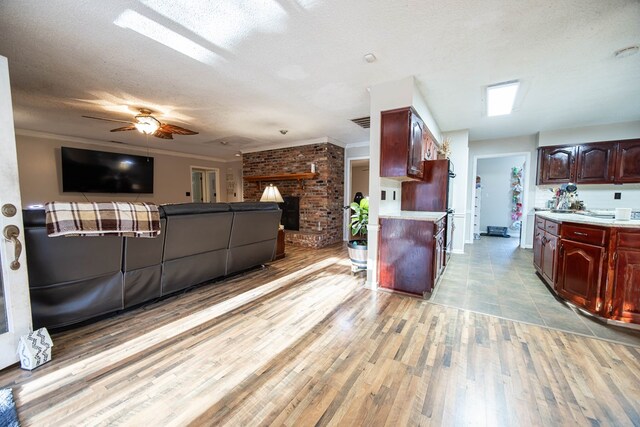 kitchen featuring crown molding, a textured ceiling, open floor plan, and light countertops