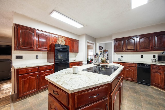 kitchen featuring light stone countertops, black appliances, decorative backsplash, and a center island